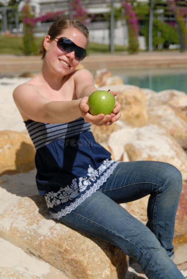Beautiful young girl offering green apple