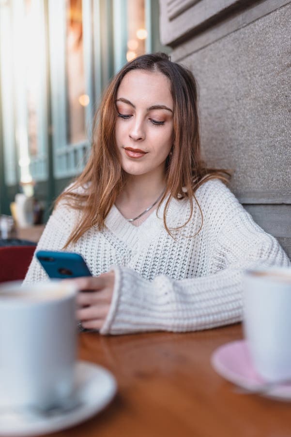 Beautiful young girl in outdoor uses smart phone and texting