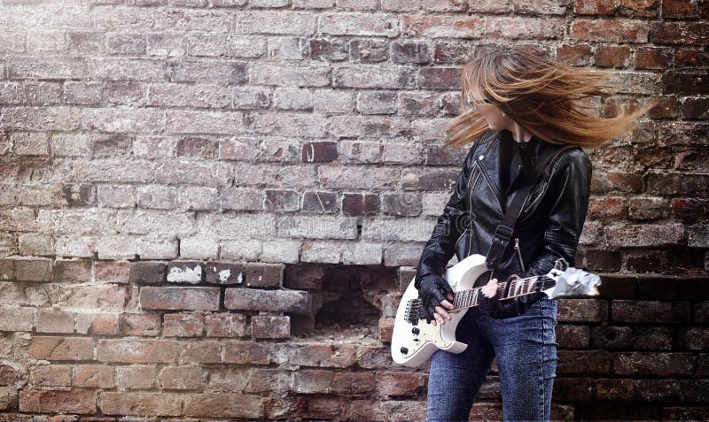 Beautiful young girl rocker with electric guitar. A rock musicia