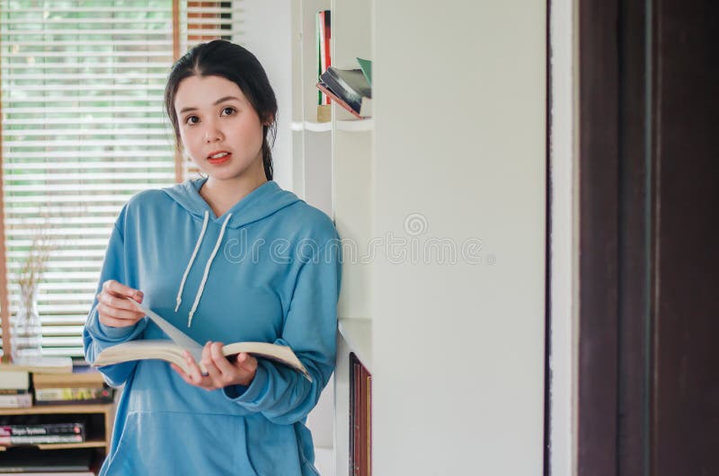 Beautiful young girl standing in the library at home with books, Woman reading a book