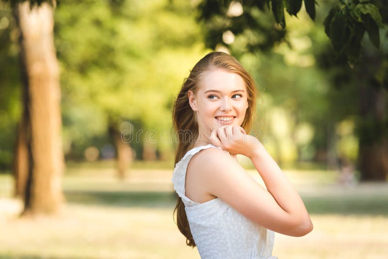 Young Girl in White Dress Posing while Standing in Park and Looking ...