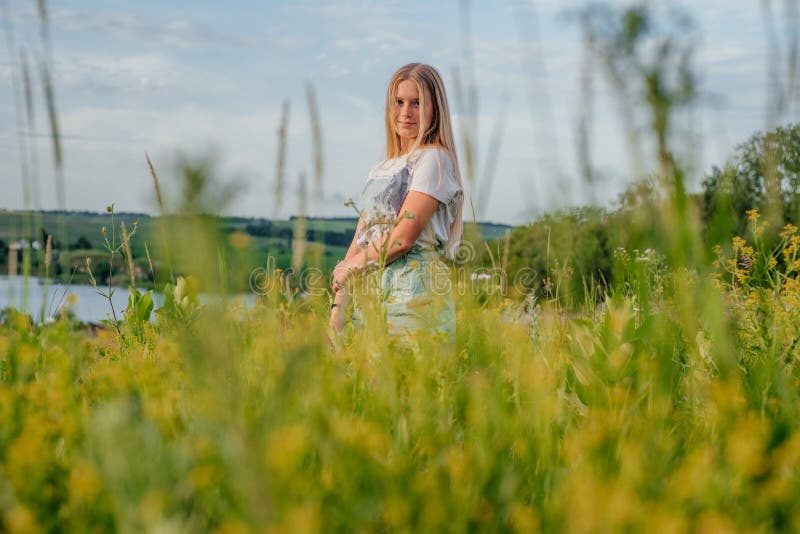 A beautiful young girl among yellow flowers at summer Ukrainian rural lanscape stock photography