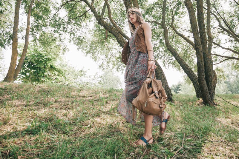 Young hippie woman walking on grass in the forest