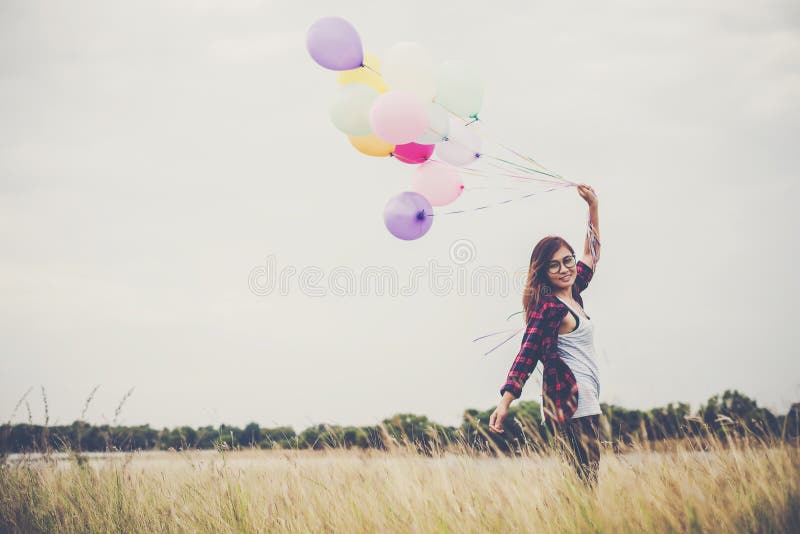 Beautiful young hipster woman holding with colorful of balloons