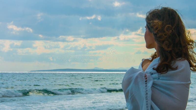 Beautiful young lady on beach looking at horizon, thinking of love, romance