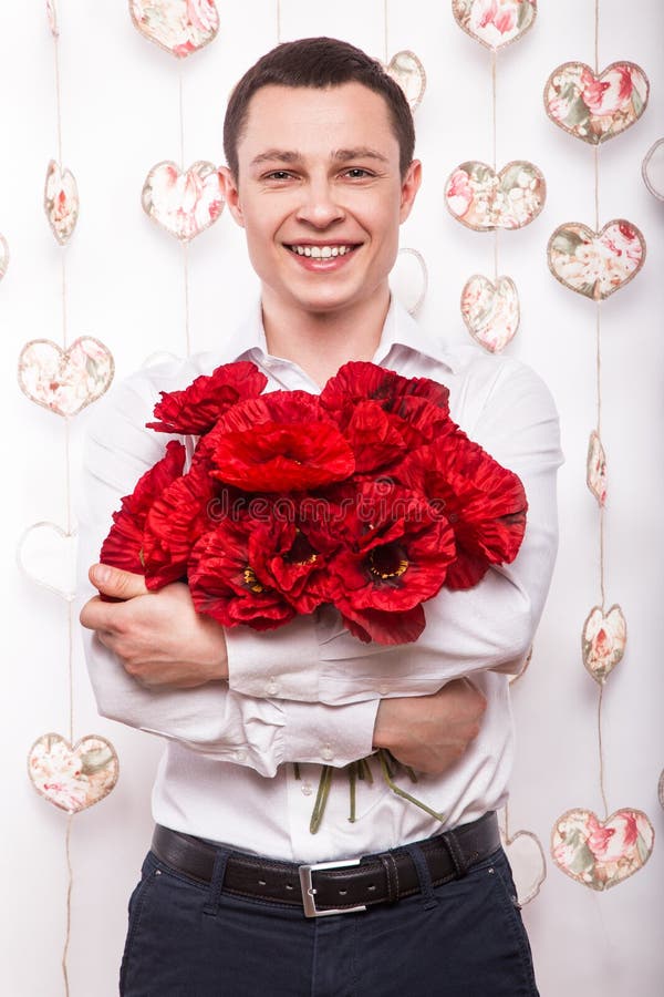 Beautiful young man in love with a bouquet of flowers. Valentine s Day.