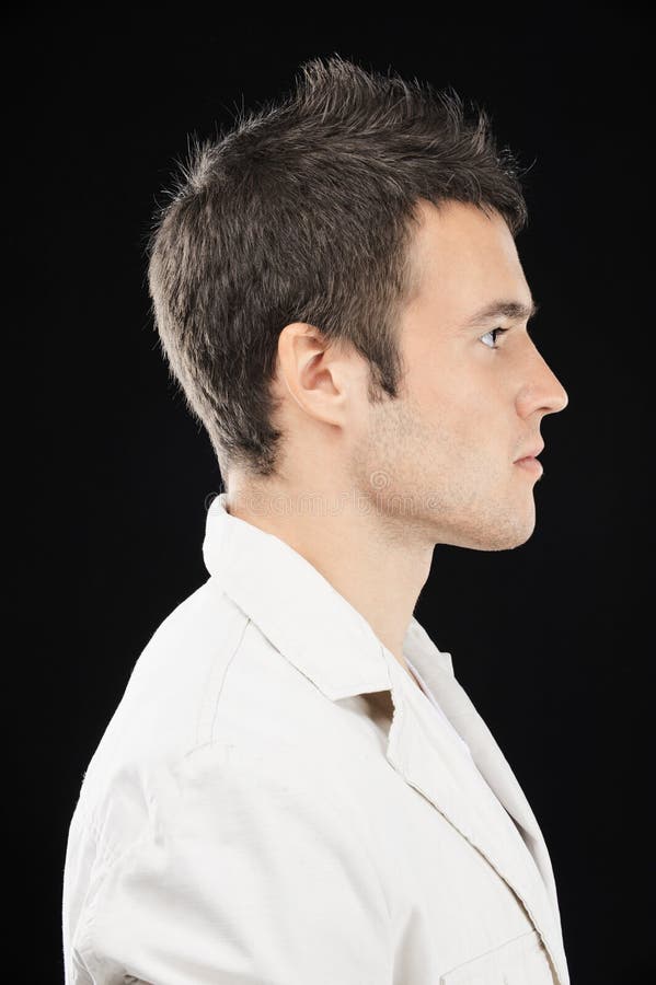 Retrato hermoso joven hombre en blanco un traje en perfil, sobre un fondo negro.