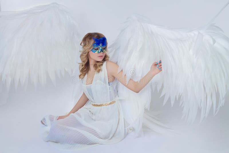 Beautiful young model with big angel wings sitting in the studio royalty free stock photo Beautiful young model with big angel wings sitting in the studio royalty free stock photo