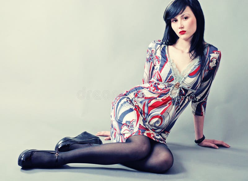 Beautiful young model with long black hair sitting on floor