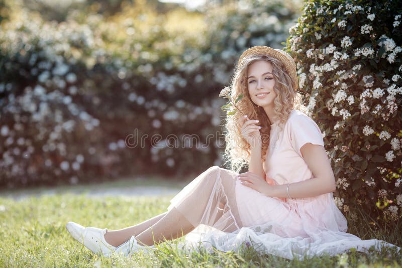 Attractive young woman in a straw hat alone in a blooming spring park stock photo Attractive young woman in a straw hat alone in a blooming spring park stock photo