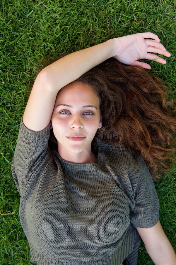 Beautiful young model staring while lying on grass