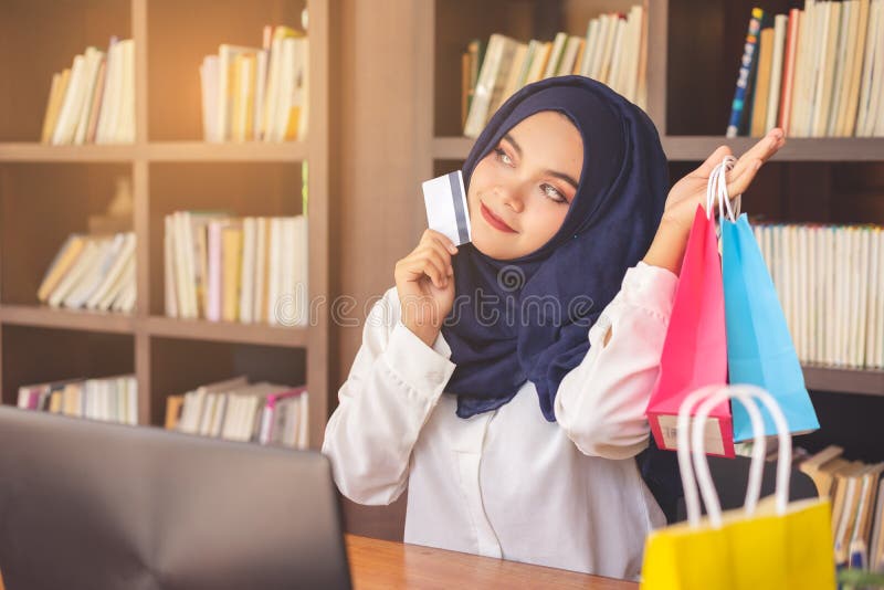 Beautiful young muslim woman showing a credit card and colorful paper shopping bags.
