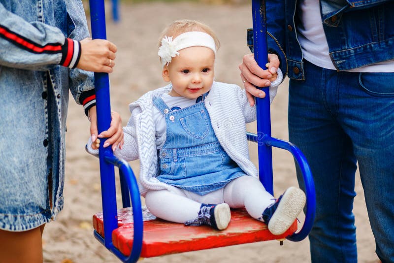Beautiful young parents, walk with a child, swing him on a swing, have fun and enjoy each other, happy family for a walk stock images Beautiful young parents, walk with a child, swing him on a swing, have fun and enjoy each other, happy family for a walk stock images