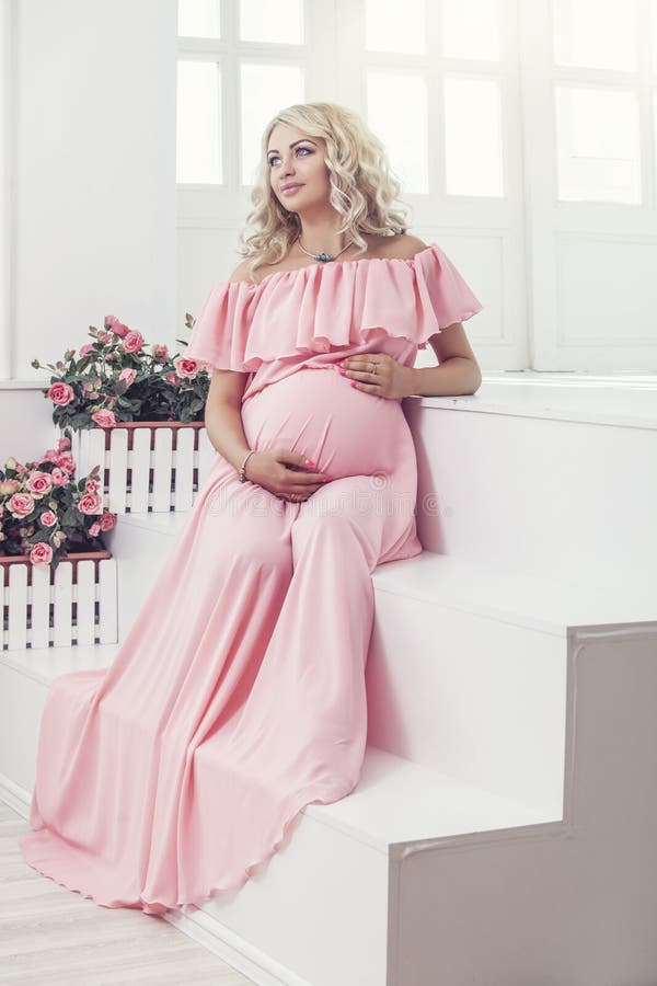 Beautiful young pregnant woman in fashionable dress in a interior royalty free stock photos Beautiful young pregnant woman in fashionable dress in a interior royalty free stock photos