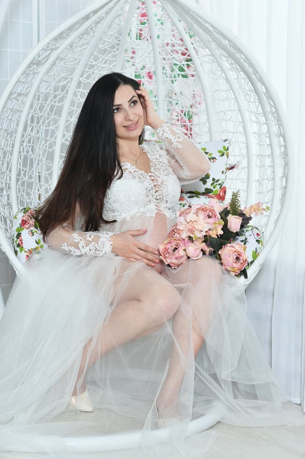 Portrait of beautiful young pregnant woman posing on swing stock photo Portrait of beautiful young pregnant woman posing on swing stock photo