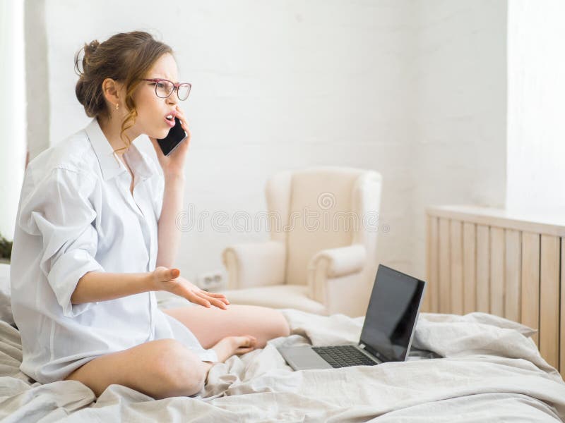 Beautiful young pregnant woman sitting on bed using technology devices: laptop and phone in modern room. Future mom stock photo Beautiful young pregnant woman sitting on bed using technology devices: laptop and phone in modern room. Future mom stock photo