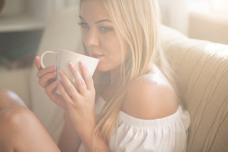 Beautiful young woman relaxing at living room while enjoying in coffee.