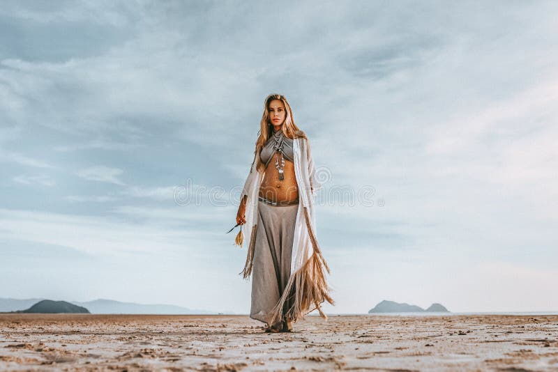 Beautiful young stylish pregnant woman with boho accessories walking on the beach at sunset stock image Beautiful young stylish pregnant woman with boho accessories walking on the beach at sunset stock image