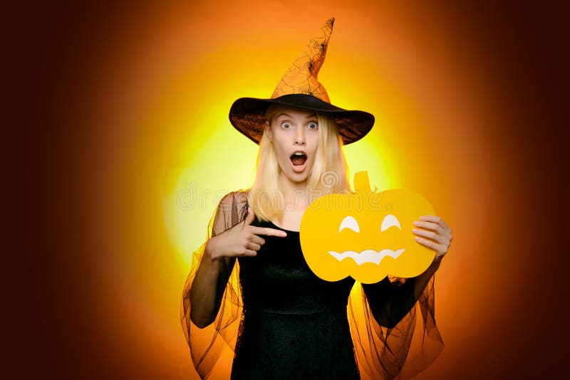 Beautiful young surprised woman in witches hat and costume pointing hand - showing products. Halloween Woman portrait stock image Beautiful young surprised woman in witches hat and costume pointing hand - showing products. Halloween Woman portrait stock image
