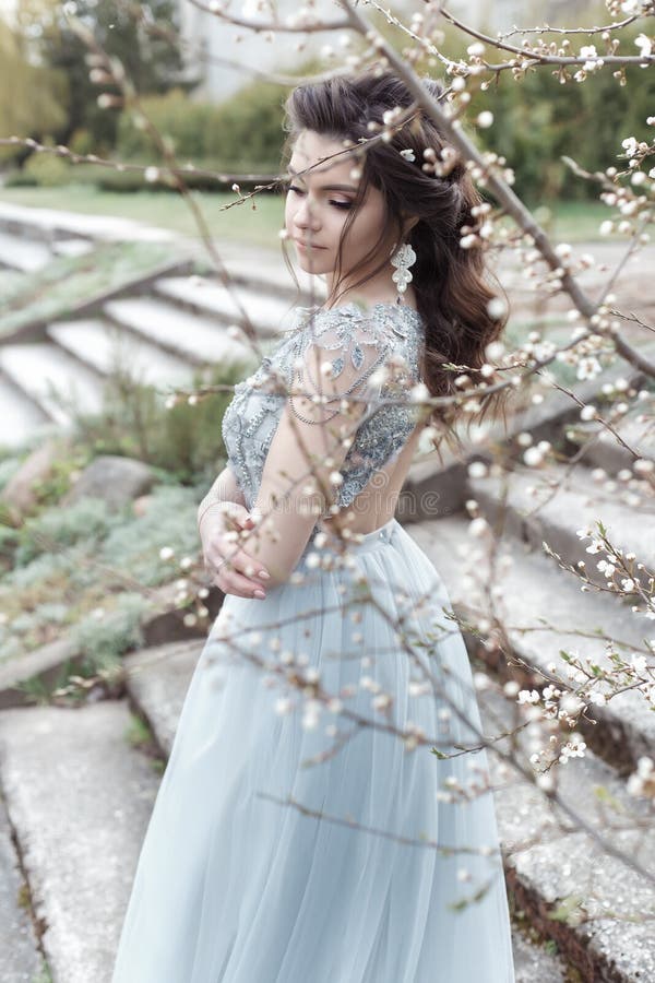 Beautiful young tender gay girl with beautiful wedding hairstyle with a snow-white smile in light dress is walking in spring royalty free stock photo Beautiful young tender gay girl with beautiful wedding hairstyle with a snow-white smile in light dress is walking in spring royalty free stock photo