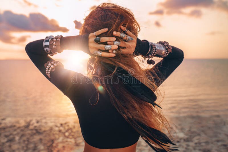 Beautiful young tribal style woman on the beach at sunset