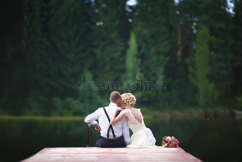Beautiful young wedding couple sitting on the pier. royalty free stock photos Beautiful young wedding couple sitting on the pier. royalty free stock photos