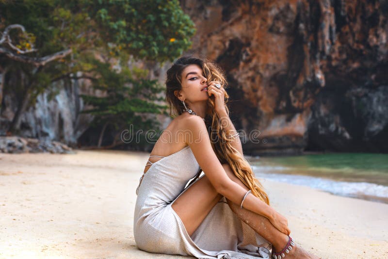 Beautiful young woman on the beach with rock background royalty free stock image