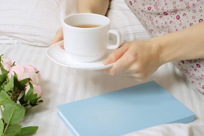 Beautiful young woman in bed drinking tea reading book stock photography Beautiful young woman in bed drinking tea reading book stock photography