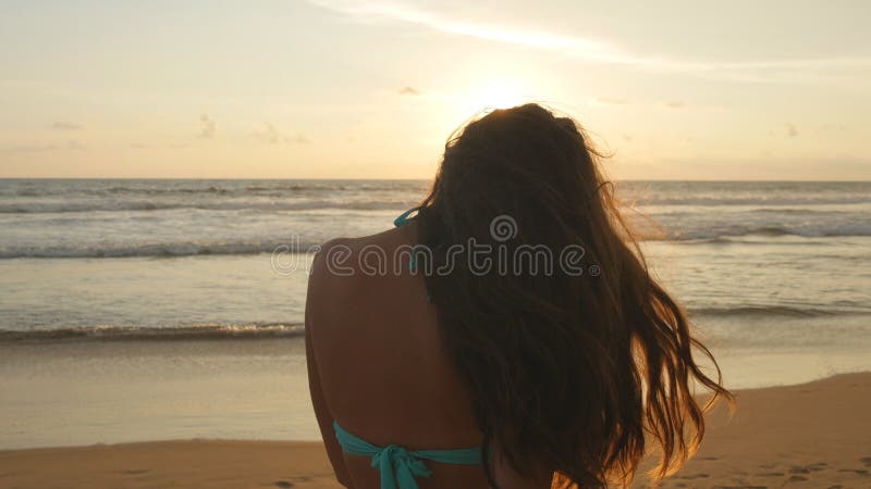 Beautiful young woman in bikini standing near the sea on sunset. Attractive girl with long hair posing on the ocean royalty free stock image Beautiful young woman in bikini standing near the sea on sunset. Attractive girl with long hair posing on the ocean royalty free stock image