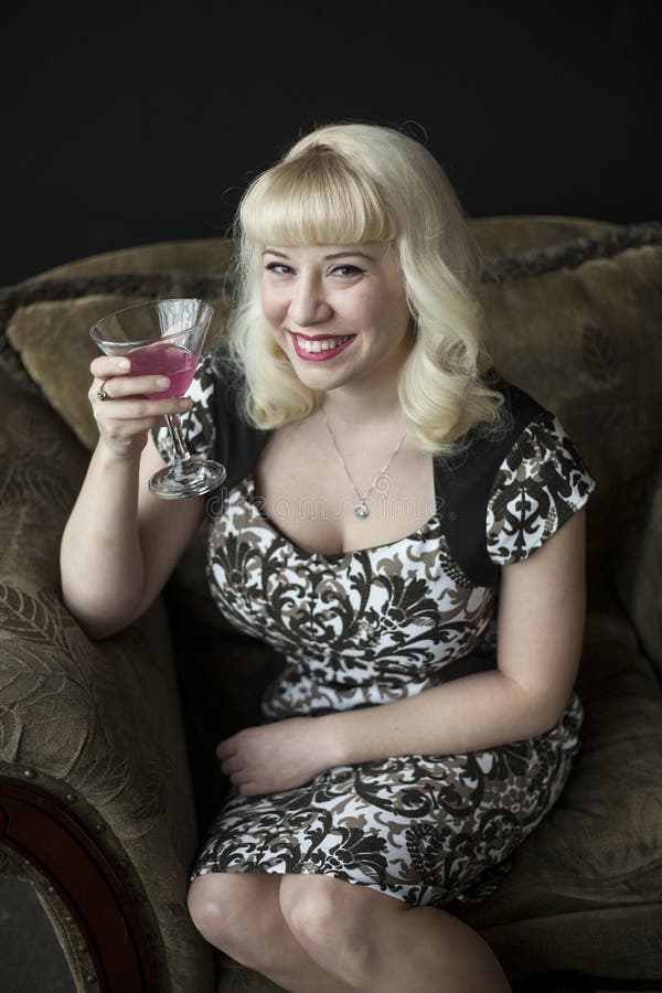 Beautiful Young Woman With Blond Hair Drinking A Pink Martini Stock