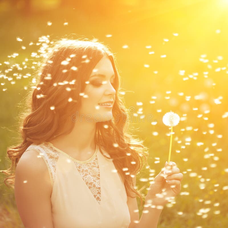 Beautiful young woman blowing dandelion. Trendy young girl at s
