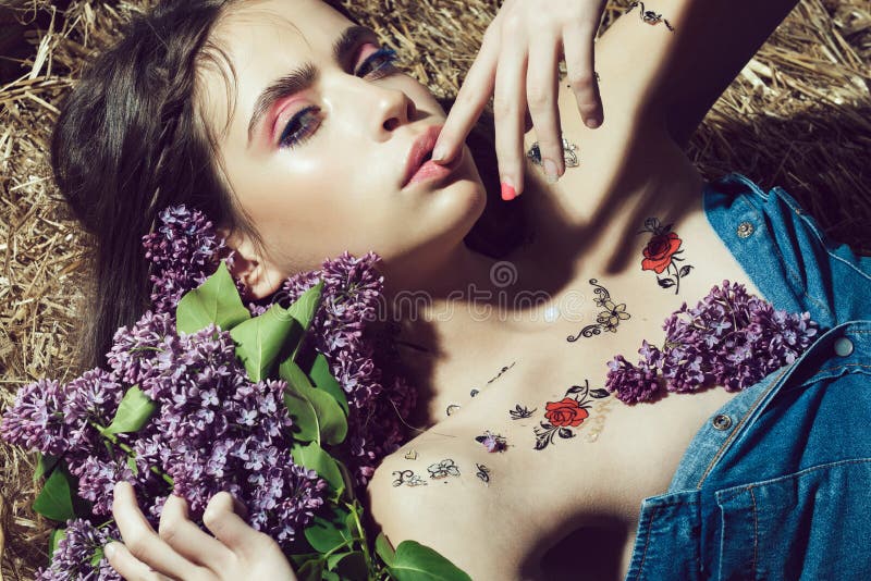 Beautiful young woman with bouquet of lilac flowers with fashion makeup. Pretty girl with fashionable makeup and red