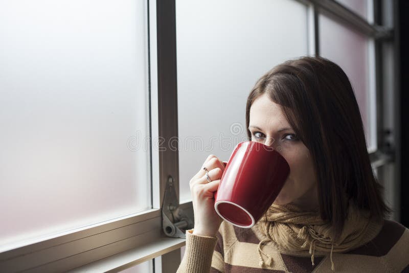 Beautiful Young Woman with Brown Hair and Eyes Holding Red Coffee Cup