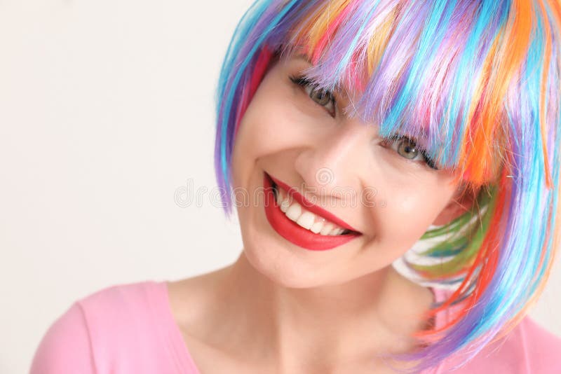 Beautiful young woman with colorful hair on light background