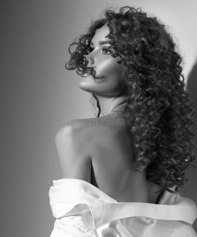 Beautiful young woman with curly hair posing, beauty model portrait, closeup. Beautiful sexy model girl in white cotton shirt