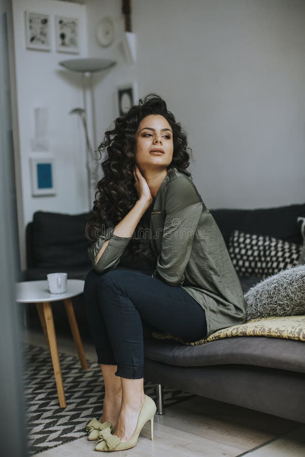 Beautiful young woman sitting by the table in the room stock photo Beautiful young woman sitting by the table in the room stock photo