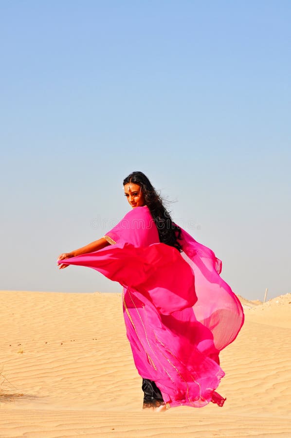 Beautiful young woman dancing in arabic desert