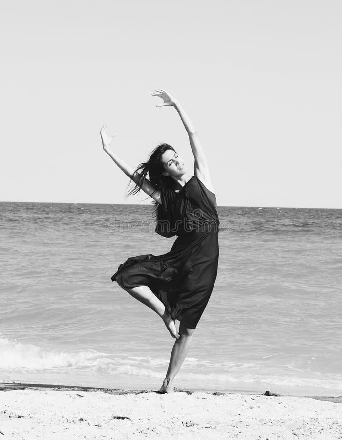 Beautiful young woman dancing on the beach