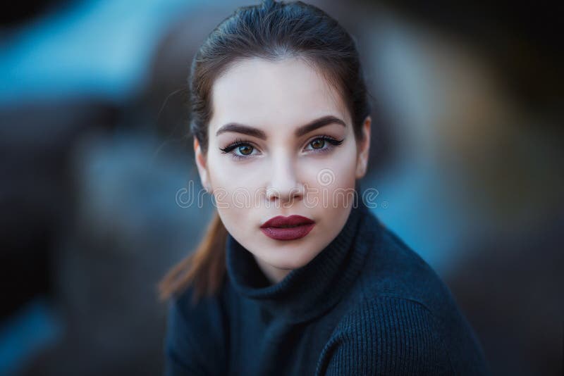 Beautiful young woman. Dramatic outdoor portrait of sensual brunette female with long hair. Sad and serious girl.