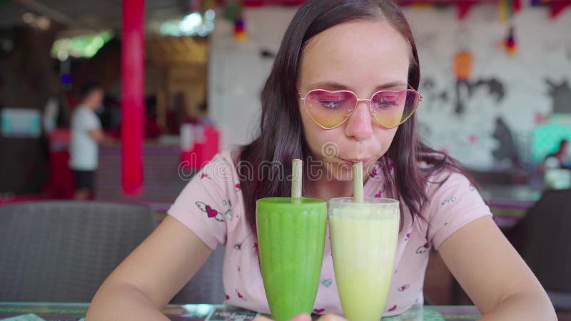 A Beautiful Young Woman Is Drinking The Healthy Smoothies In A Tropical Cafe The Girl Is 