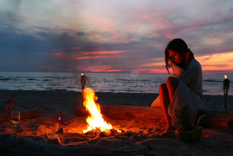 Beautiful young woman drinking wine on beach