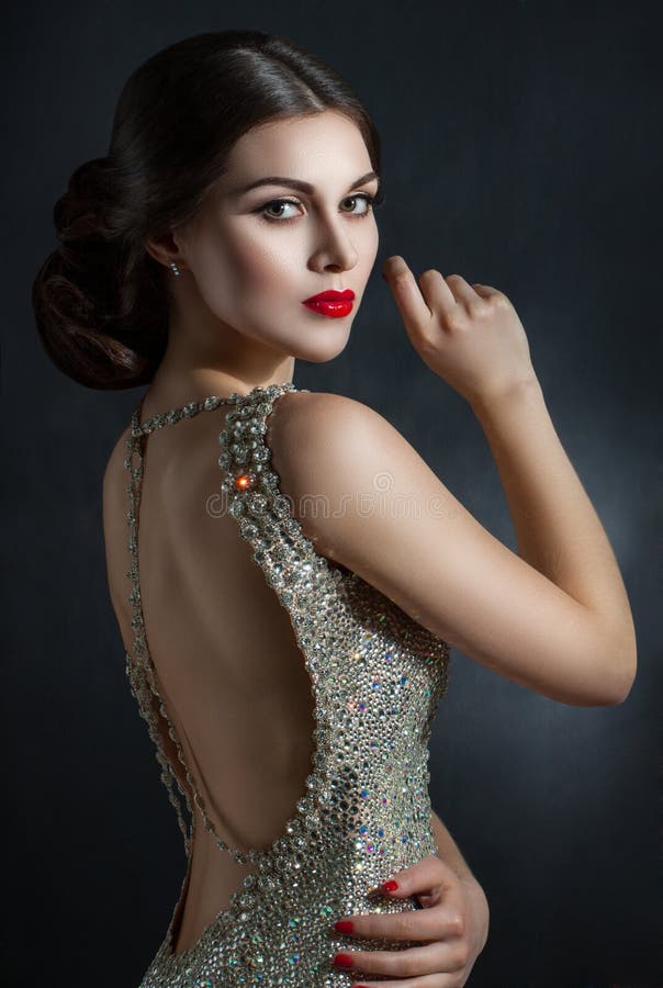 Beautiful young woman in an evening dress crystal. Perfect beauty, red lips, bright makeup. Twinkling sparkling stones on dress. Hair in a beautiful hairstyle