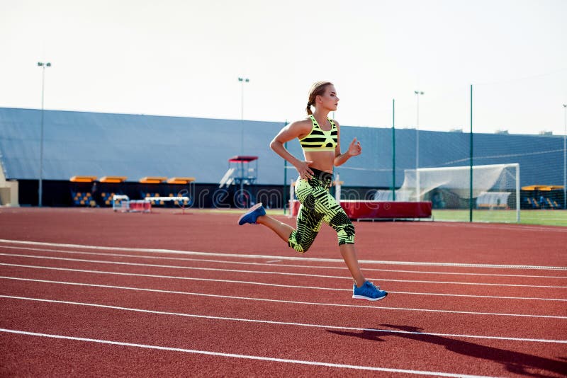 Beautiful young woman exercise jogging and running on athletic track on stadium.