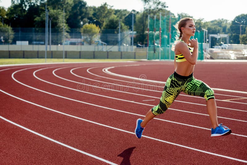 Beautiful young woman exercise jogging and running on athletic track on stadium.