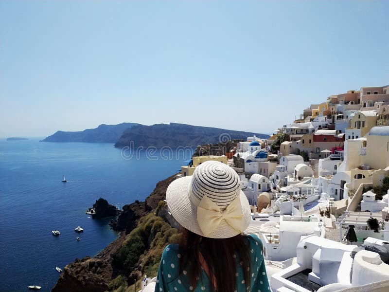 Beautiful young woman in green dotted dress walking in Oia, Santorini streets. White houses, blue sea royalty free stock photos Beautiful young woman in green dotted dress walking in Oia, Santorini streets. White houses, blue sea royalty free stock photos