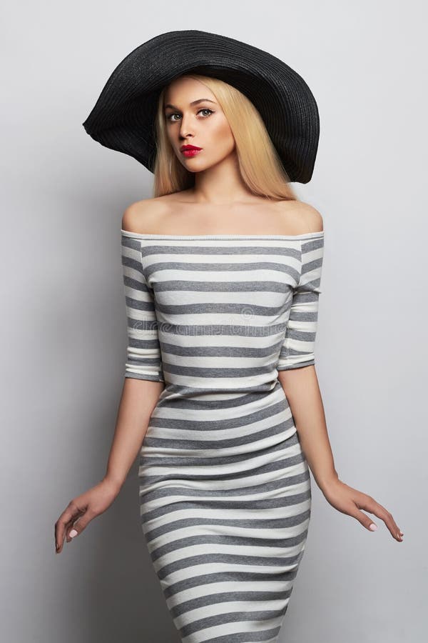 Beautiful young woman in hat. summer fashion girl in trendy striped dress