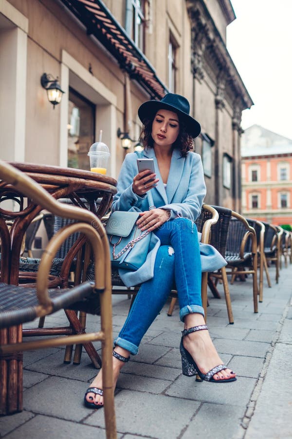 Beautiful young woman having orange juice in outdoor cafe while using smartphone royalty free stock photo Beautiful young woman having orange juice in outdoor cafe while using smartphone royalty free stock photo