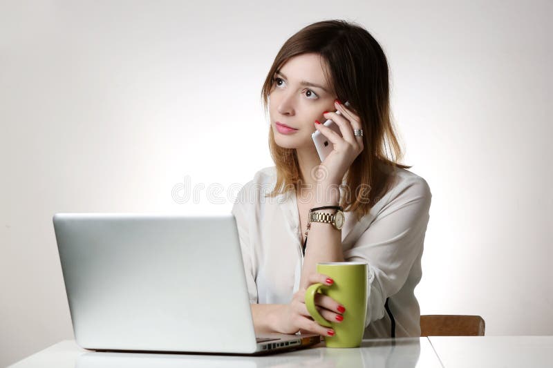 Attractive business woman in the front of her laptop having a phone conversation. Attractive business woman in the front of her laptop having a phone conversation