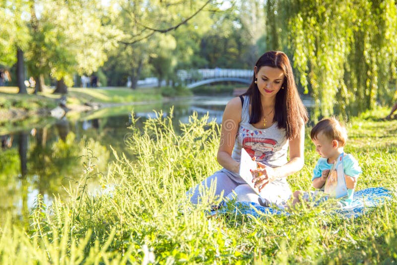 Beautiful young woman and her adorable little son play in sunny park, read books royalty free stock photo Beautiful young woman and her adorable little son play in sunny park, read books royalty free stock photo