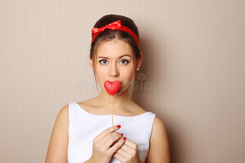 Beautiful young woman holding a red heart